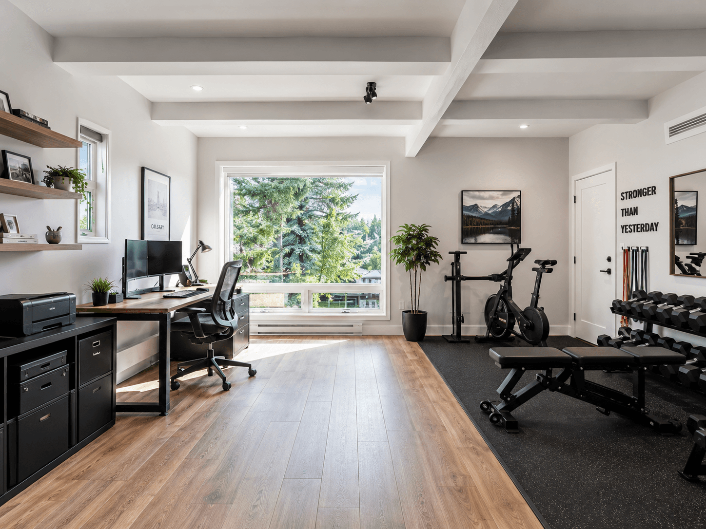 Converted Calgary garage suite with a home office on one side featuring a wood desk and dual monitors, and a home gym on the other with a bike, bench, and free weights, wide plank flooring throughout.